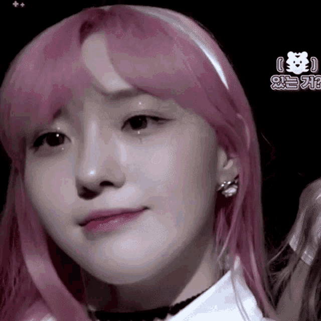 a close up of a woman 's face with pink hair and earrings