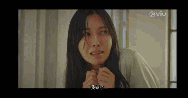 a woman is sitting in a room with her hands on her face and looking at the camera .