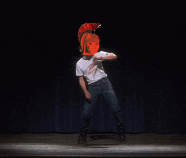 a man wearing an orange helmet and a white shirt is dancing on a stage