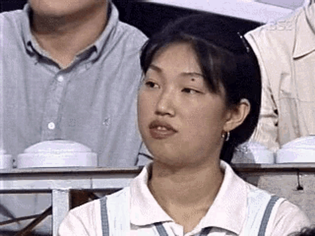 a woman is sitting in a row of people watching a game and making a funny face .