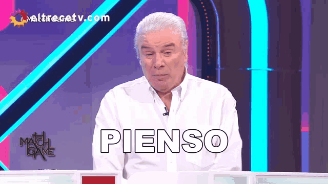 a man in a white shirt is sitting in front of a screen that says " pienso "