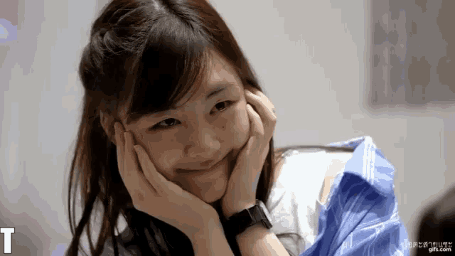 a girl with her hands on her face is smiling with the letter t behind her