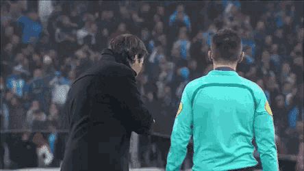 a man in a blue shirt is standing next to another man in a black jacket .