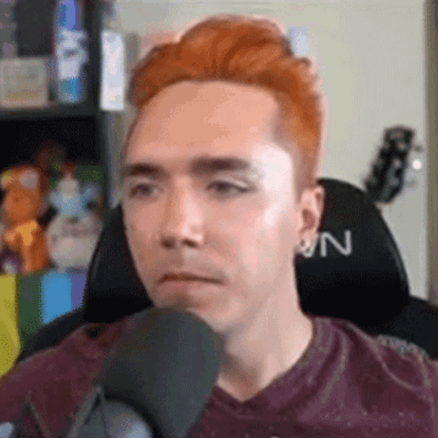 a man with red hair is sitting in front of a microphone and making a funny face .