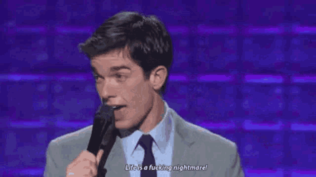 a man in a suit and tie is holding a microphone and talking into it .