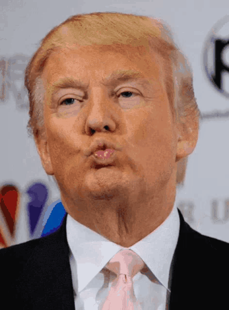 donald trump is wearing a pink tie and making a funny face