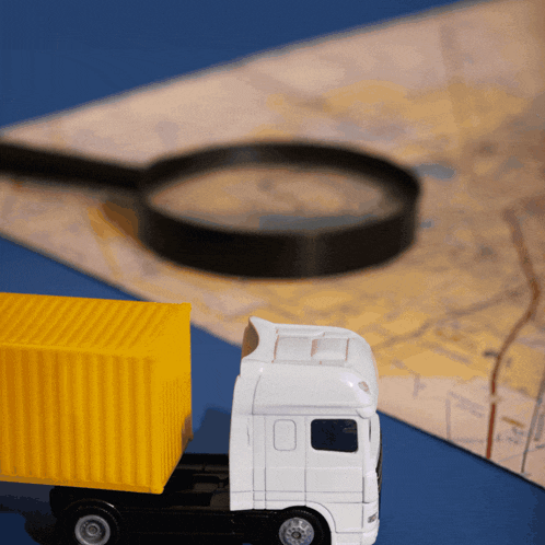 a toy truck sits next to a magnifying glass on a map