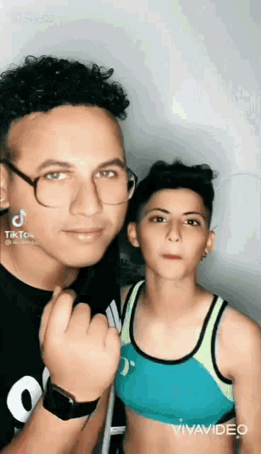 a man and a boy are posing for a picture together . the boy is wearing a crop top .