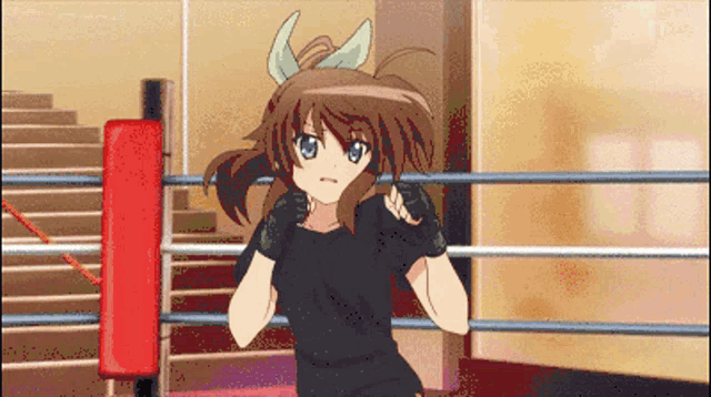 a girl in a black shirt is in a boxing ring with a red punching bag