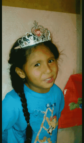 a young girl wearing a tiara and a blue shirt