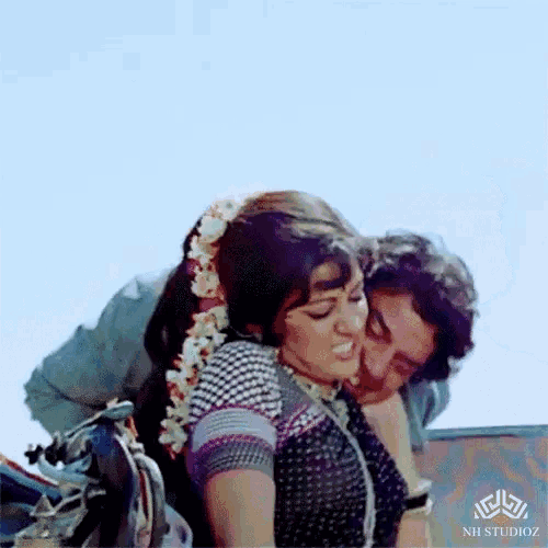 a man is kissing a woman on the cheek with a nh studioz logo in the corner