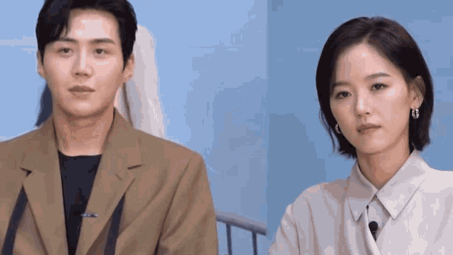 a man and a woman are standing next to each other in front of a blue wall