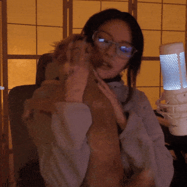 a woman wearing glasses is holding a brown dog in her arms