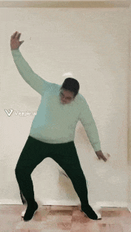 a man in a blue sweater and black pants is dancing in a room
