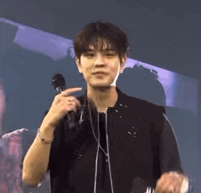 a young man is holding a microphone in his hand while wearing headphones .