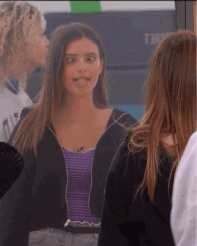 a woman wearing a purple top and a black jacket is sticking out her tongue