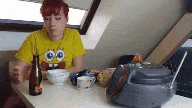 a woman in a spongebob shirt sits at a table