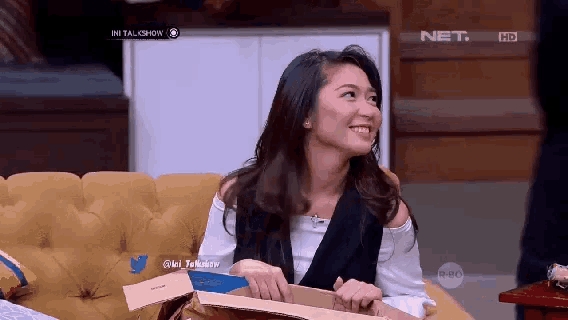 a woman sitting on a couch with a box in front of her and the words net hd on the bottom