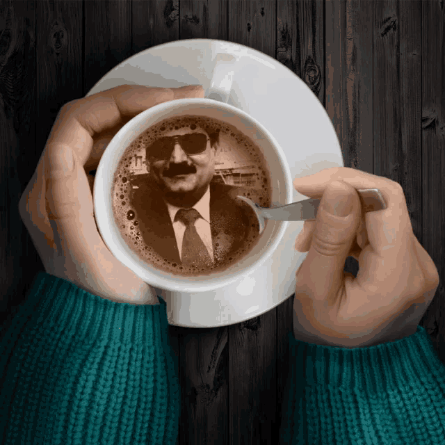 a person is holding a cup of coffee with a picture of a man in a suit and tie on it