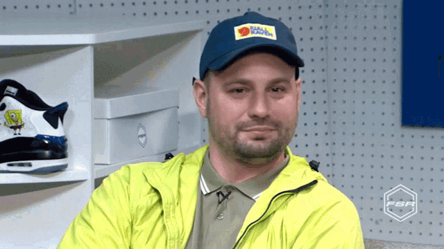 a man wearing a yellow jacket and a blue hat that says fjällräven