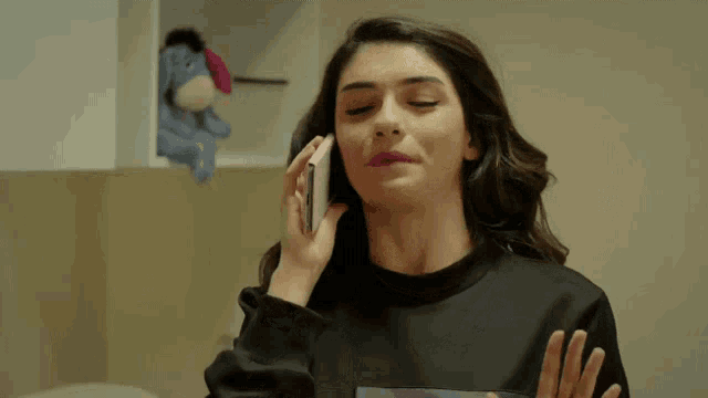 a woman is talking on a cell phone in front of a stuffed animal