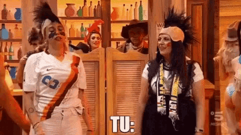 two women are standing next to each other in front of a saloon door and one of them is saying tu .