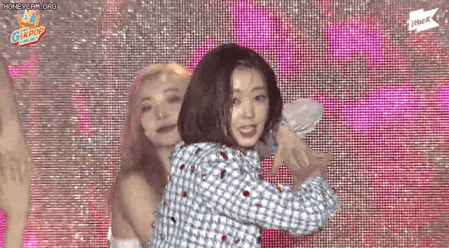 two women are dancing in front of a screen that says gkpop