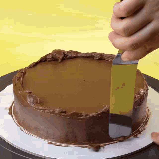 a person is spreading chocolate frosting on a cake