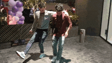 two men are dancing in front of a purple balloon display