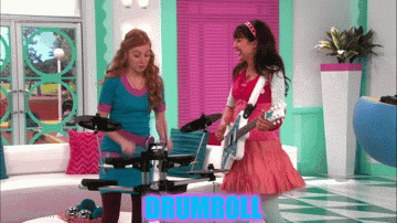 two girls are playing drums and one is holding a guitar and the word drumroll is on the screen