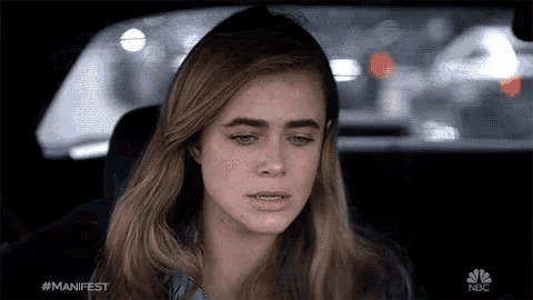 a woman sitting in a car with the hashtag #manifest on her face
