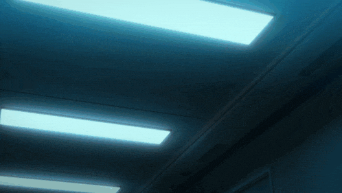 a dark hallway with a row of lights on the ceiling