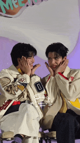two young men are sitting next to each other and one of them has the number 0 on his jacket