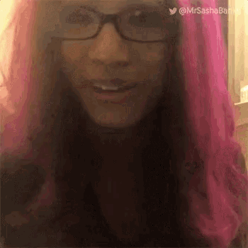 a woman with pink hair and glasses is making a funny face .