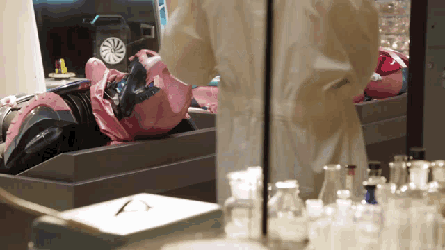 a person in a lab coat is standing in front of a container with a pink object in it