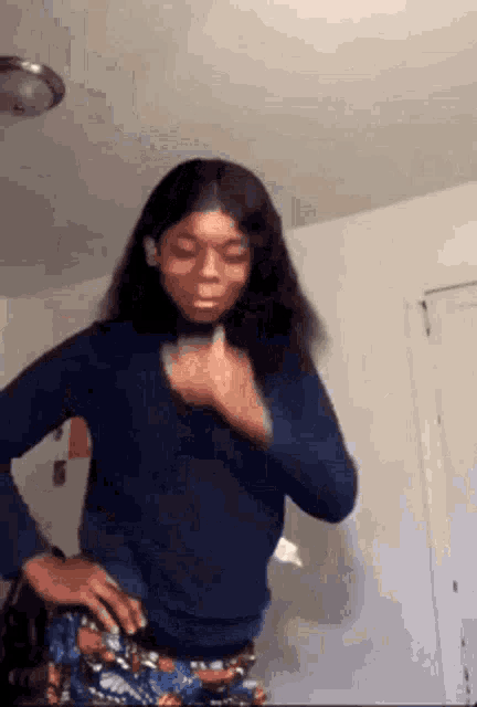 a woman is standing in a room with her hands on her hips and making a funny face .