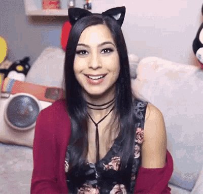 a woman wearing cat ears and a choker smiles at the camera