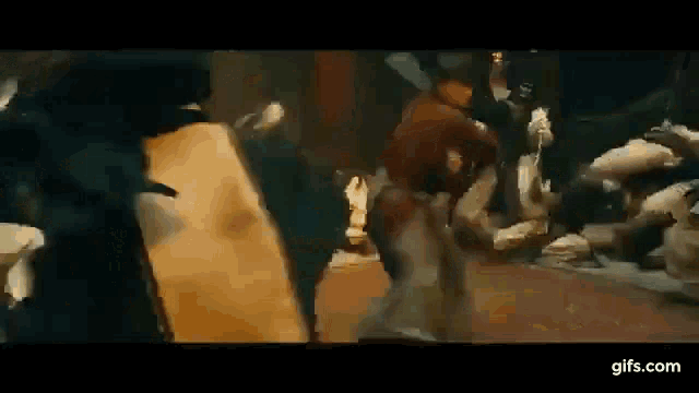 a group of people are fighting each other on a street in a movie scene .