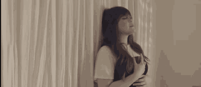 a woman is leaning against a white curtain with her eyes closed