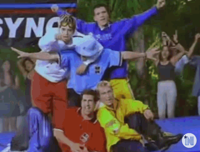 a group of young men are posing for a picture while sitting on a trampoline .