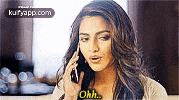 a woman is talking on a cell phone with the words ohh written on her chest .