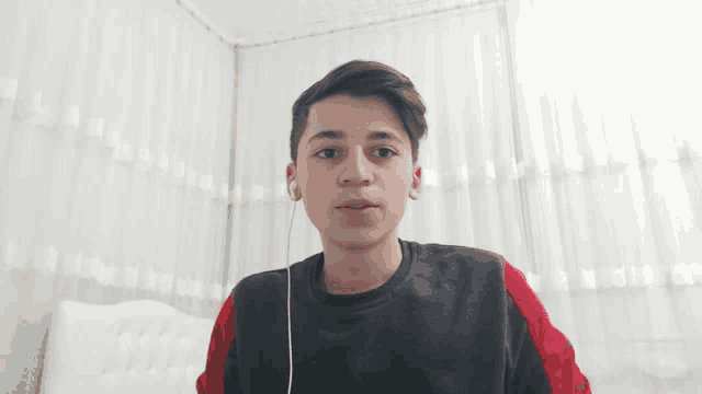 a young boy wearing ear buds is sitting on a bed