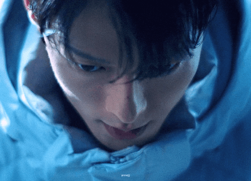 a close up of a person 's face with a blue background and a watermark that says ' ainmei '