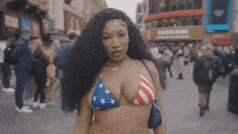 a woman wearing an american flag bikini is walking down a street .