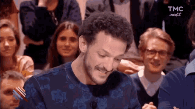 a man is making a funny face in front of a crowd .