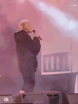 a man is singing into a microphone on stage .