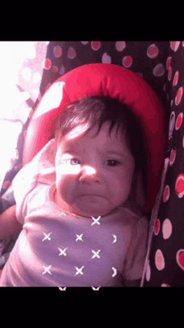 a baby in a pink shirt with x 's on it looks angry