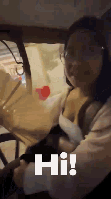 a woman sitting in a car with the word hi written on the screen
