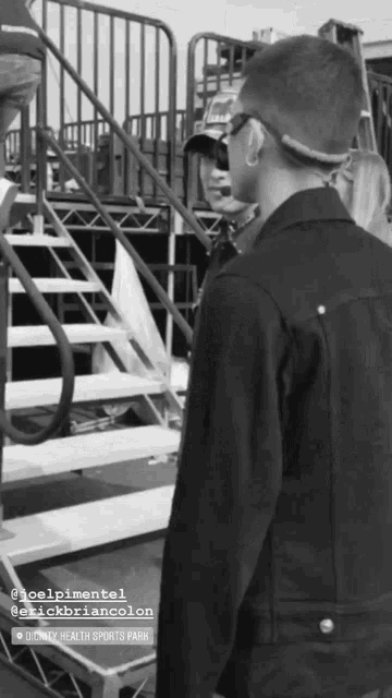 a black and white photo of a man standing in front of stairs with the name joelpimentel written on the bottom