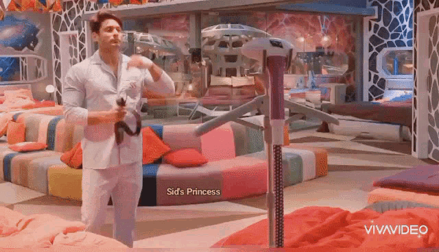 a man in a white suit is standing in a room with a vacuum cleaner in his hand .